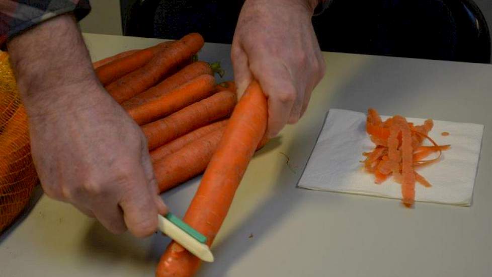 Bram Harpe van Agrifirm Plant haalt met een dunschiller van elke peen een dikke laag af.