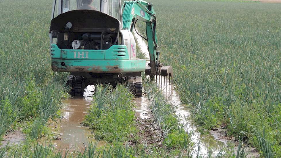 Akkerbouwer Jan Groenenberg uit Werkendam heeft een kraantje gehuurd om zijn uienland vrij van water te kunnen krijgen.