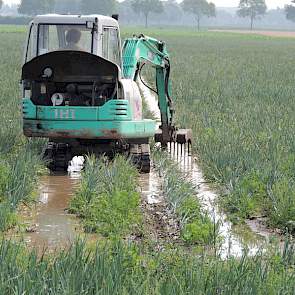 Akkerbouwer Jan Groenenberg uit Werkendam heeft een kraantje gehuurd om zijn uienland vrij van water te kunnen krijgen.