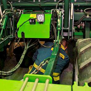 Luime kruipt onder de ruggenfrees door om ook de middelste spuitdoppen te controleren. Voordat hij dat doet, controleert hij of de hendel goed staat en de machine niet zo maar naar beneden kan zakken: veiligheid boven alles. Aansluitend zet hij de spuit u