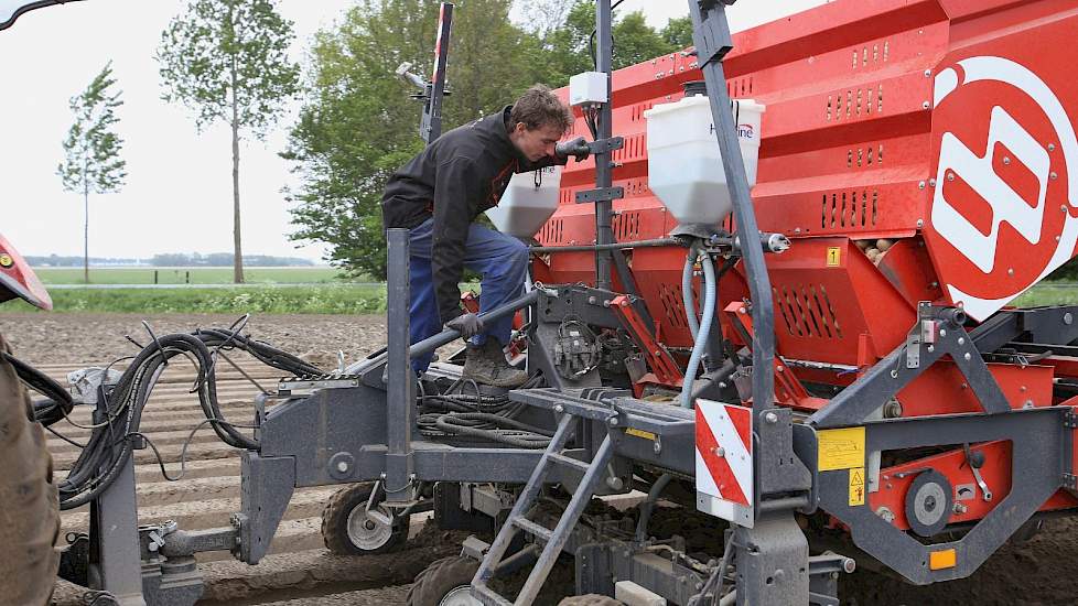 Niels Ottink controleert de instellingen van de pootmachine. Omdat de samenwerking in totaal zo'n 70 hectare pootgoed teelt, zetten ze een snarenbedpootmachine in.