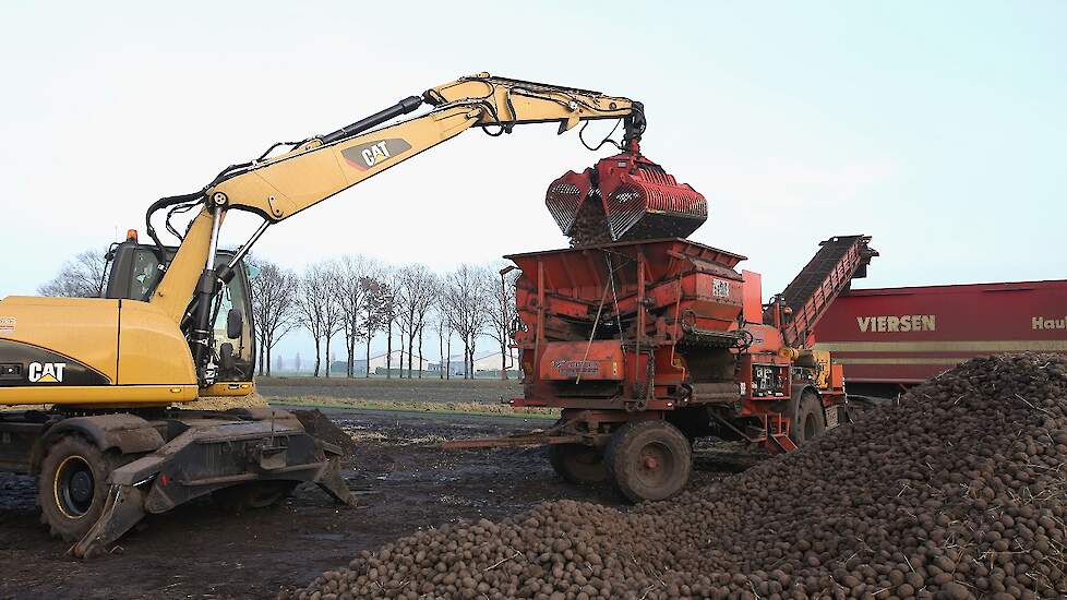 De kraan stort de aardappelen in de schoner, die ze vervolgens in de vrachtwagen stort.