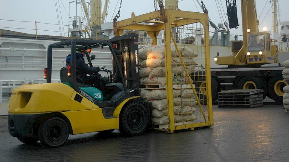 De heftruck plaatst steeds twee pallets met zakken pootgoed in de laadbak…